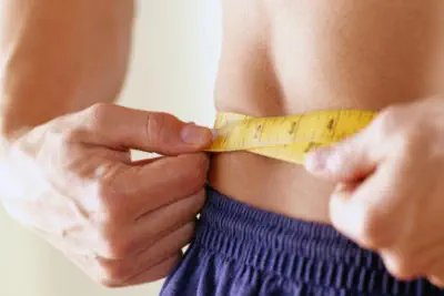 La nutricionista esta midiendo el contorno a una persona que esta haciendo dieta